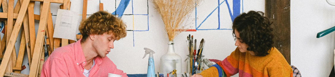 Dos personas jóvenes en un taller de pintura con pinceles